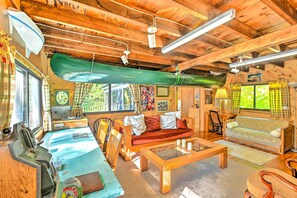A cozy cabin interior with a wooden ceiling, a sofa, a dining table, and a kitchen area. - Dreamy Bucksport Hideaway on Freshwater Pond! (Bucksport)