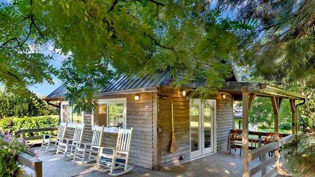 Une cabane en bois dotée d’une terrasse, d’un espace salon extérieur et d’une pergola.