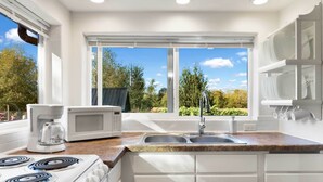 Une cuisine moderne avec des meubles blancs, une cuisinière, un four à micro-ondes et un évier.
