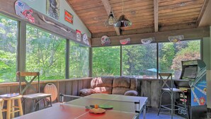 A room with a ping pong table, a couch, and a vintage arcade machine. - Cozy Sevierville Condo: Balcony, Pool Access (Sevierville)