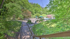A wooden deck leading to a pool area surrounded by lush greenery and trees. - Cozy Sevierville Condo: Balcony, Pool Access (Sevierville)
