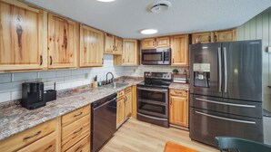 A modern kitchen with wooden cabinets, stainless steel appliances, and granite countertops. - Cozy Sevierville Condo: Balcony, Pool Access (Sevierville)