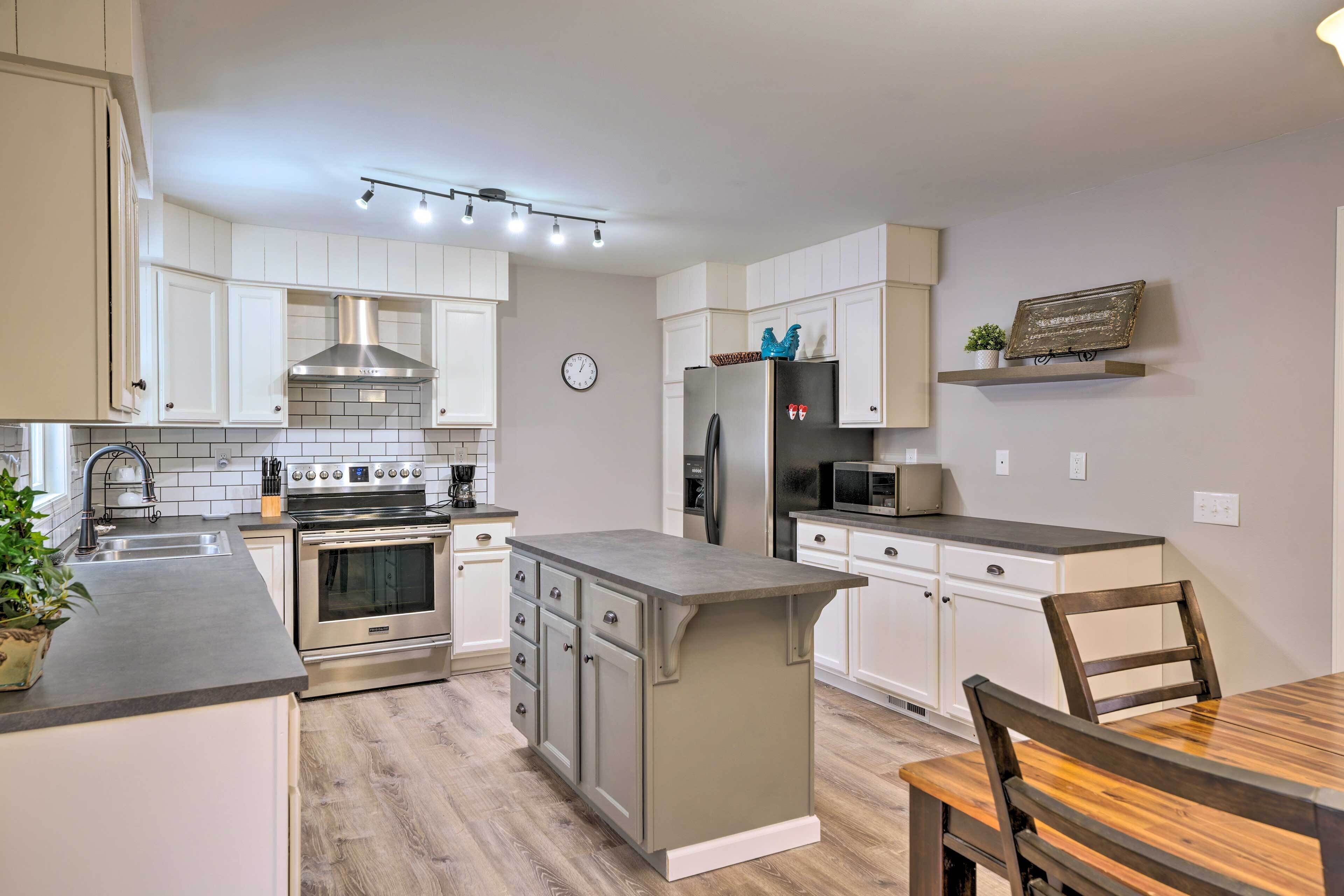 A modern kitchen with stainless steel appliances, white cabinetry, and a wooden dining table.