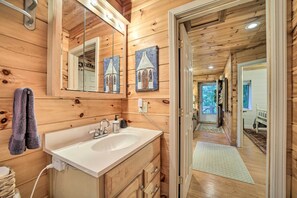 Un baño de cabaña de madera con un espejo grande, armarios de madera y un lavabo.