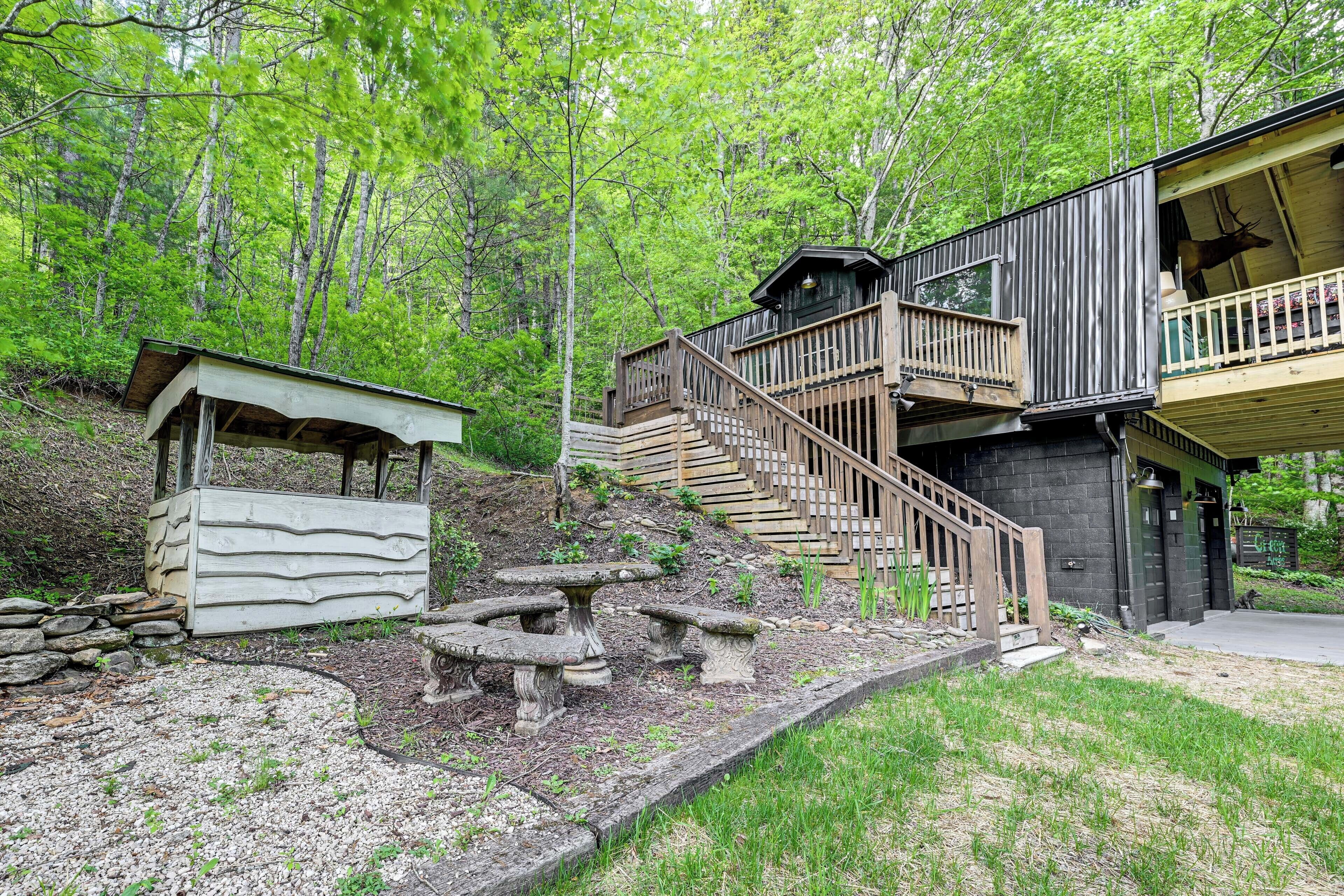 Eine Holzhütte mit einer Holzterrasse, Steinbänken und einer Treppe zu einem Balkon.