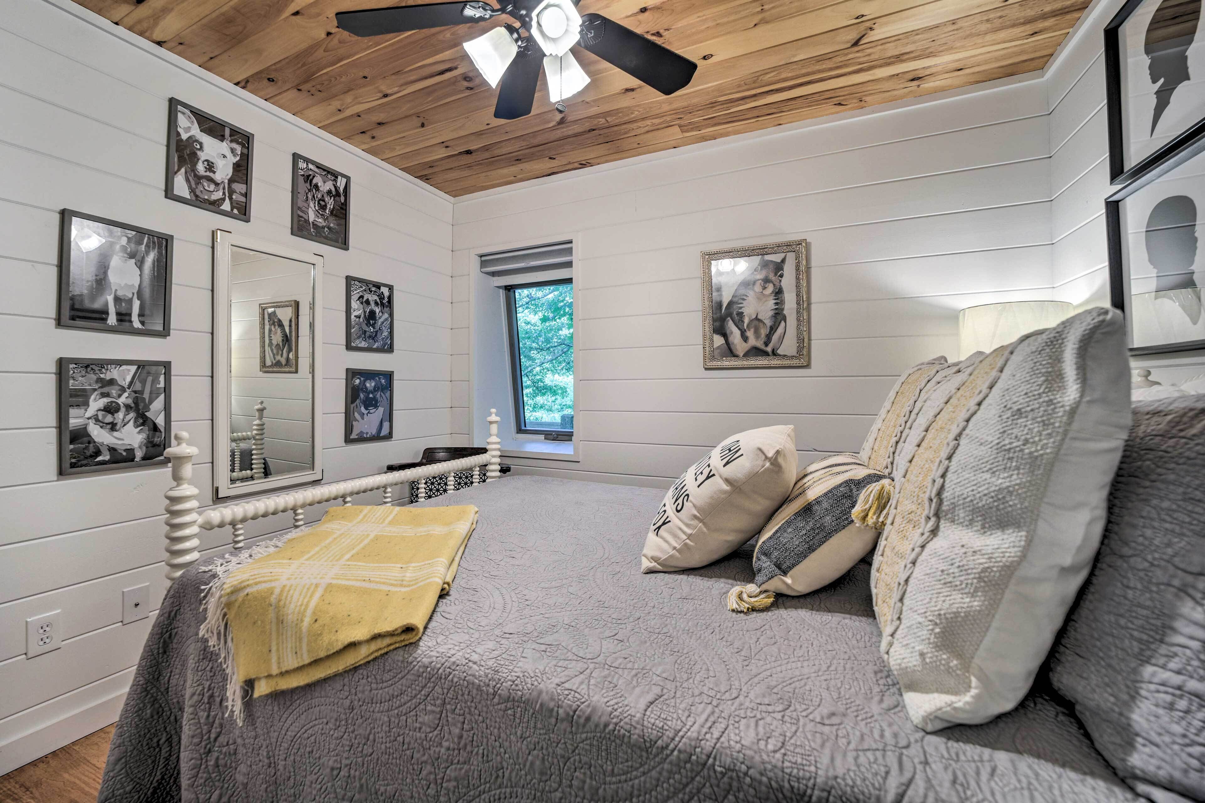 Une chambre à coucher avec un lit, un ventilateur de plafond et des tableaux encadrés accrochés aux murs.