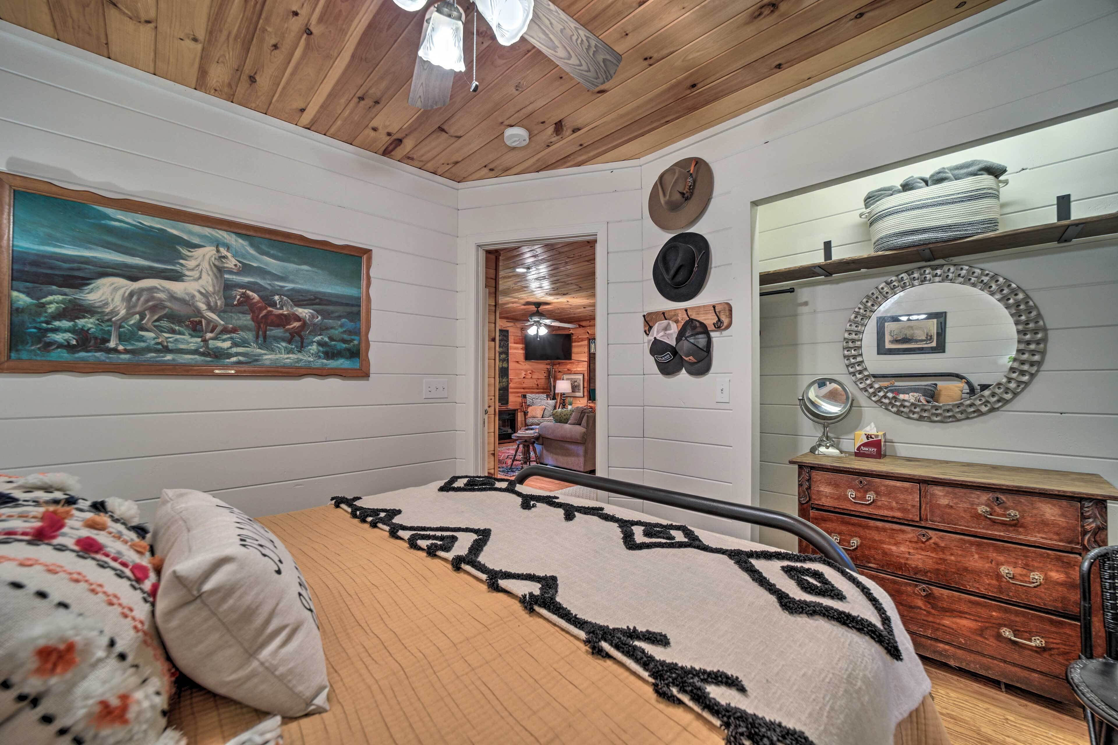 Un dormitorio con cama, un cuadro, un tocador y un espejo.