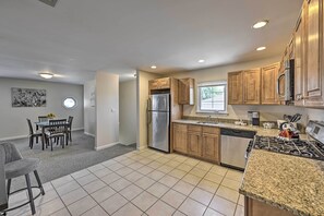 A modern kitchen with granite countertops, stainless steel appliances, and wooden cabinets. - Glen Cove Home: Walk to Boardwalk + Dining! (Glen Cove)