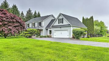 A two-story house with a garage, surrounded by a well-maintained lawn and trees.