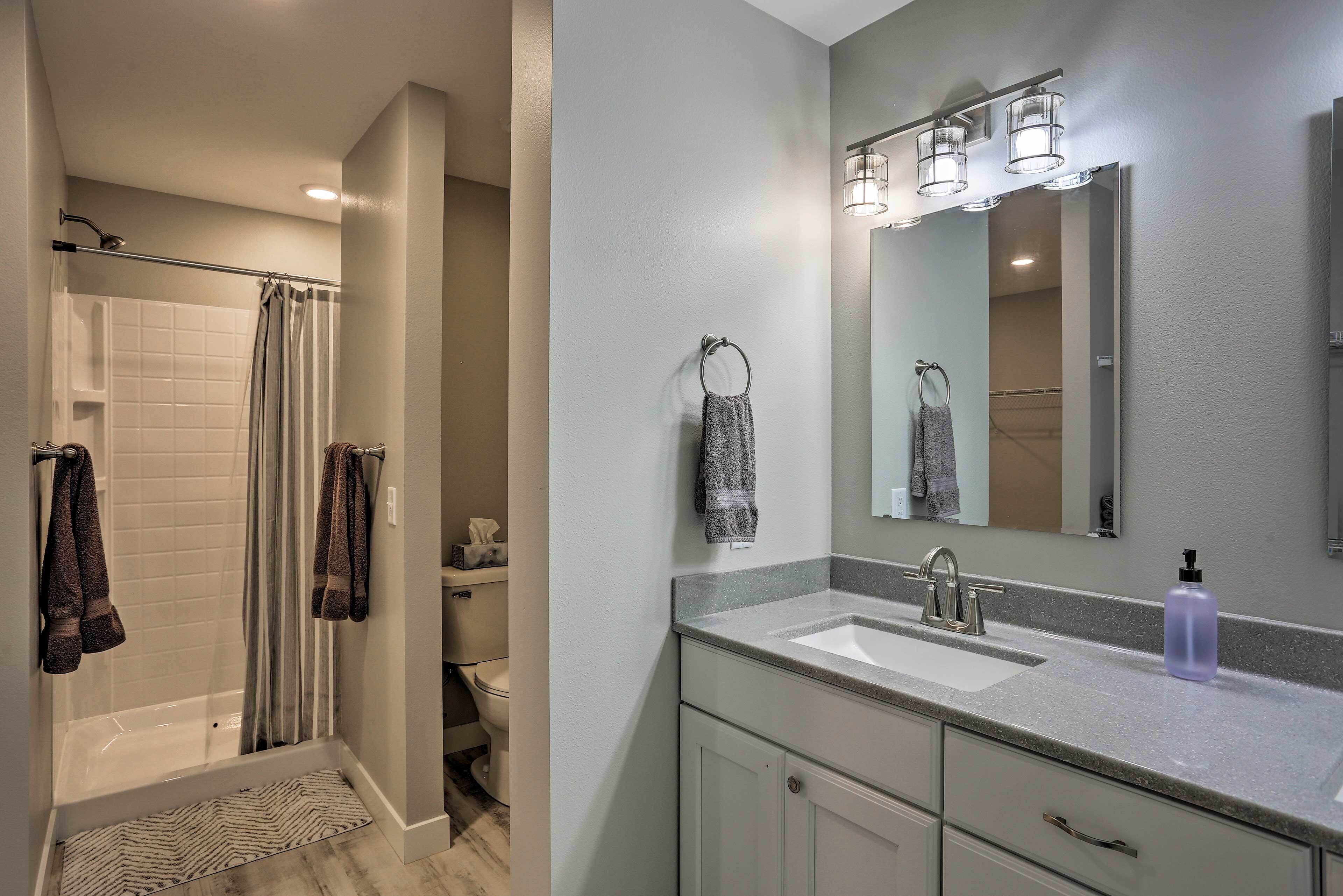 A bathroom with a shower, toilet, sink, and mirror.