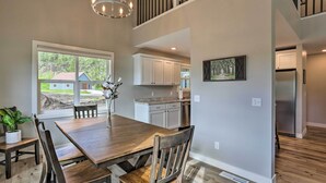A spacious dining area with a wooden table and chairs, a chandelier, and a view of the outdoors. - Heart of Black Hills Home by Mickelson Trail! (Hill City)