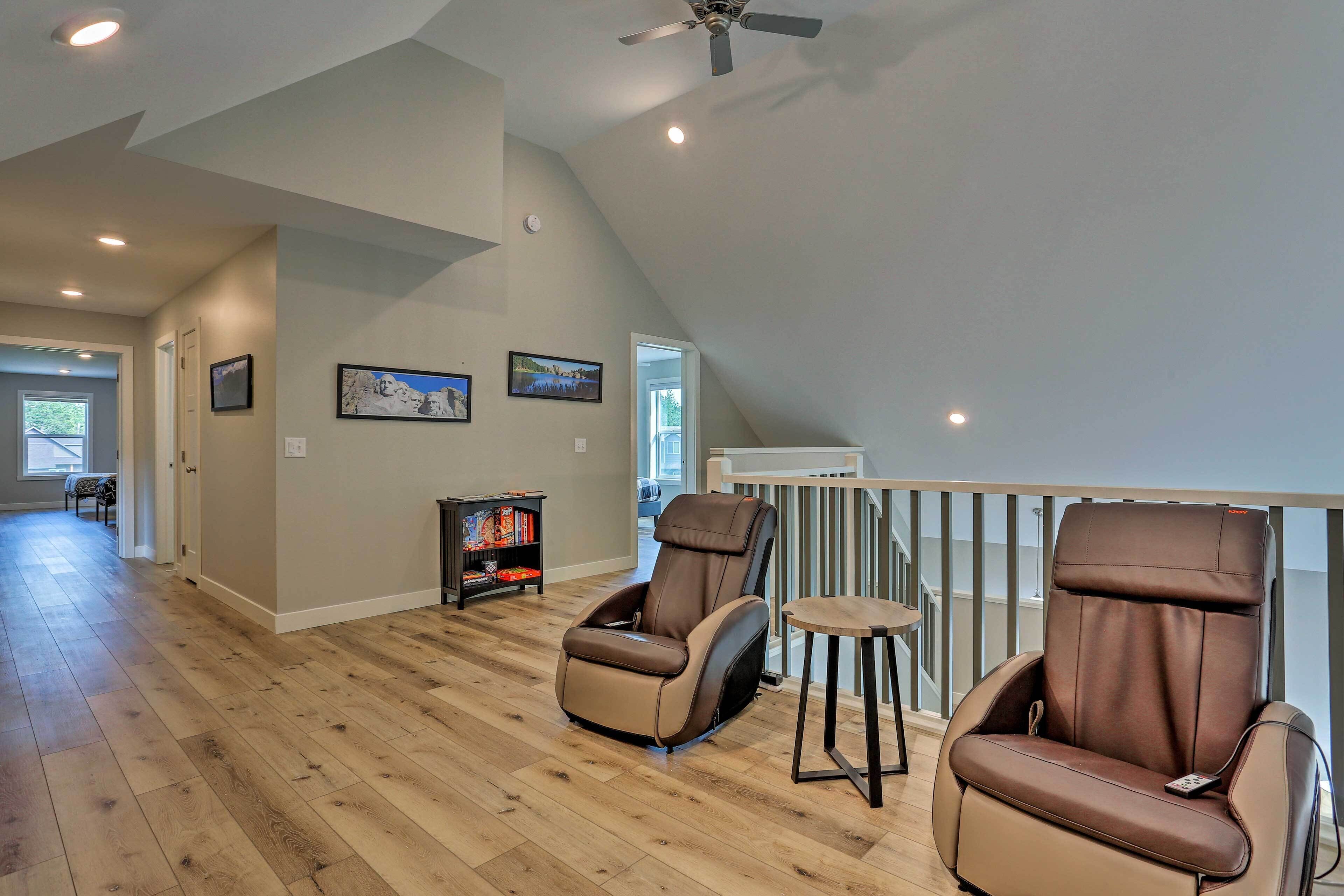 A spacious room with a high ceiling and a sloped roof, featuring two massage chairs and a small table.