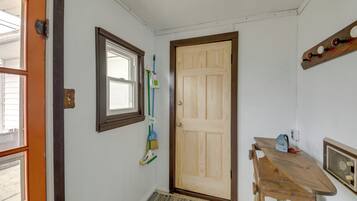 A room with a wooden door, a window, a broom, a radiator, and a table.