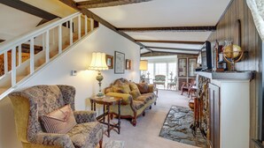 A spacious living room with a high ceiling, a staircase, and a fireplace with a globe. - Historic Alexandria Home w/ Private Yard! (Alexandria)