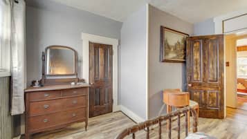 Un dormitorio con un aparador de madera, una silla, una cama y una puerta que da a otra habitación.