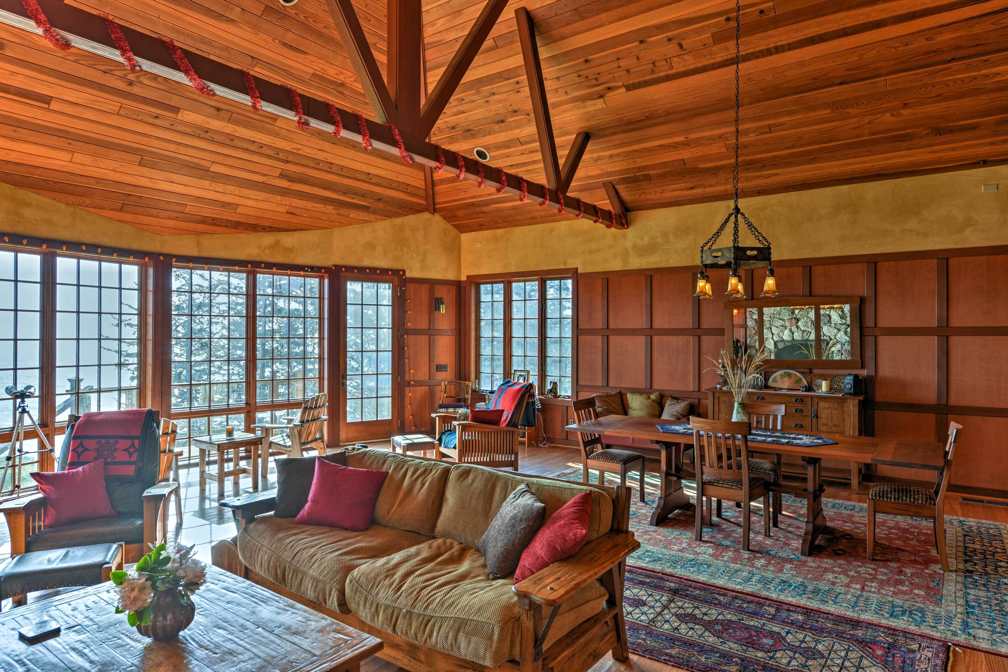 A spacious living room with wooden furniture, large windows, and a dining area.