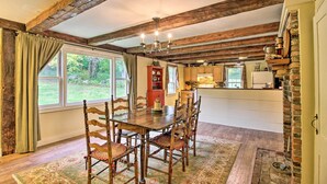 A dining area with a wooden table and chairs, a chandelier, and a view of the outdoors. - Historic Hanover Area Home, 16 Miles to Dartmouth! (Enfield)
