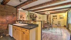 A kitchen with wooden beams, a dishwasher, and a dining area with a table and chairs. - Historic Hanover Area Home, 16 Miles to Dartmouth! (Enfield)
