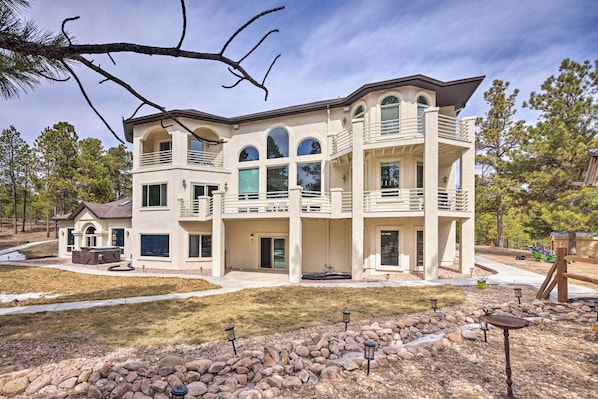 A multi-story residential building with a balcony, large windows, and a stone foundation.