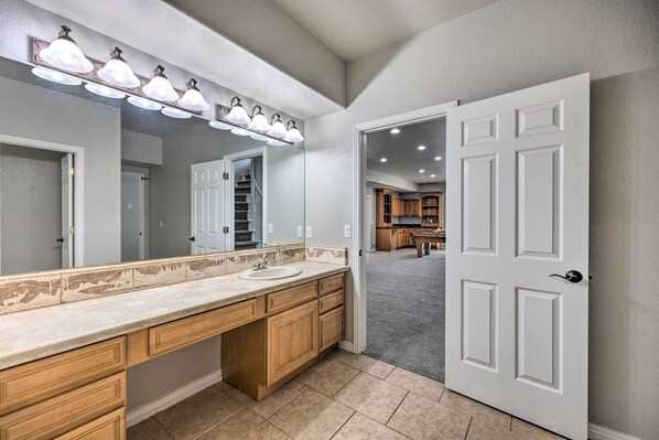 A bathroom with a large vanity, a mirror, and a light fixture above the sink.