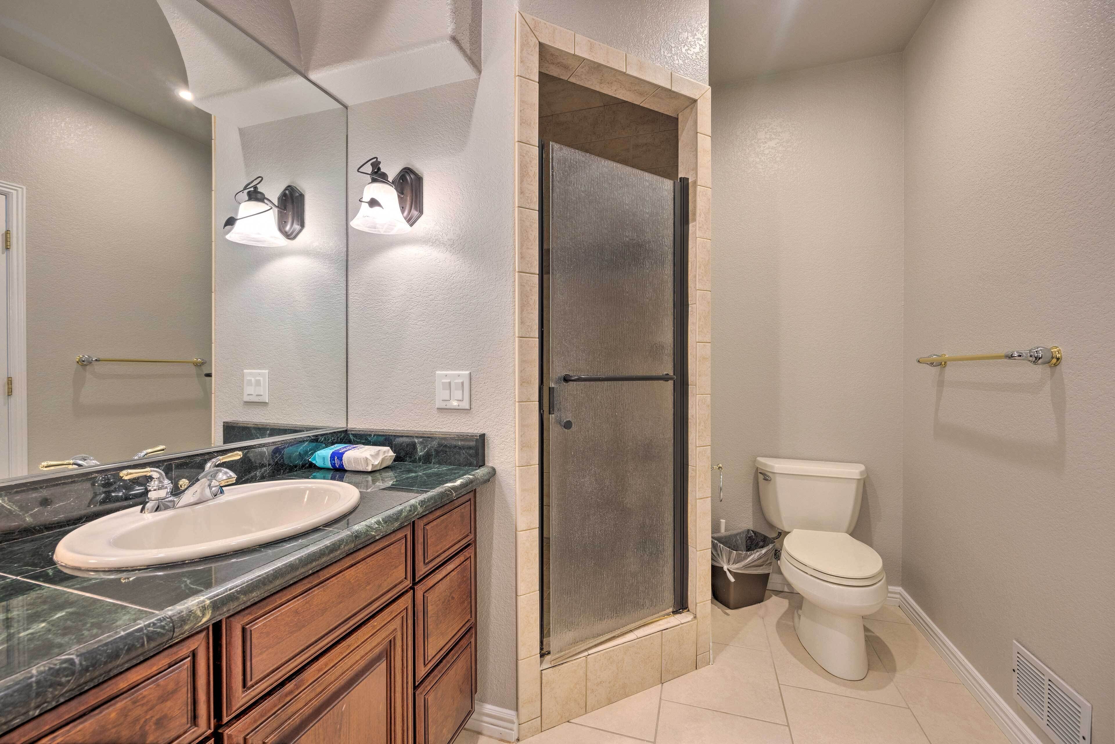 A bathroom with a double sink, a shower enclosure, and a toilet.