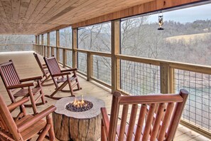 Eine Holzterrasse mit Schaukelstühlen und einem Feuerkorb mit Blick auf eine malerische Landschaft.