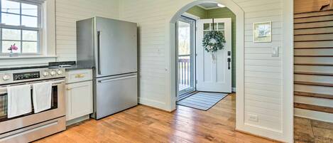 A kitchen with wooden flooring, stainless steel appliances, and a view to the outside.