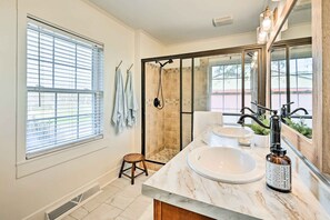 Enjoy a refreshing shower in the spacious bathroom with a large sink, shower, and mirror.