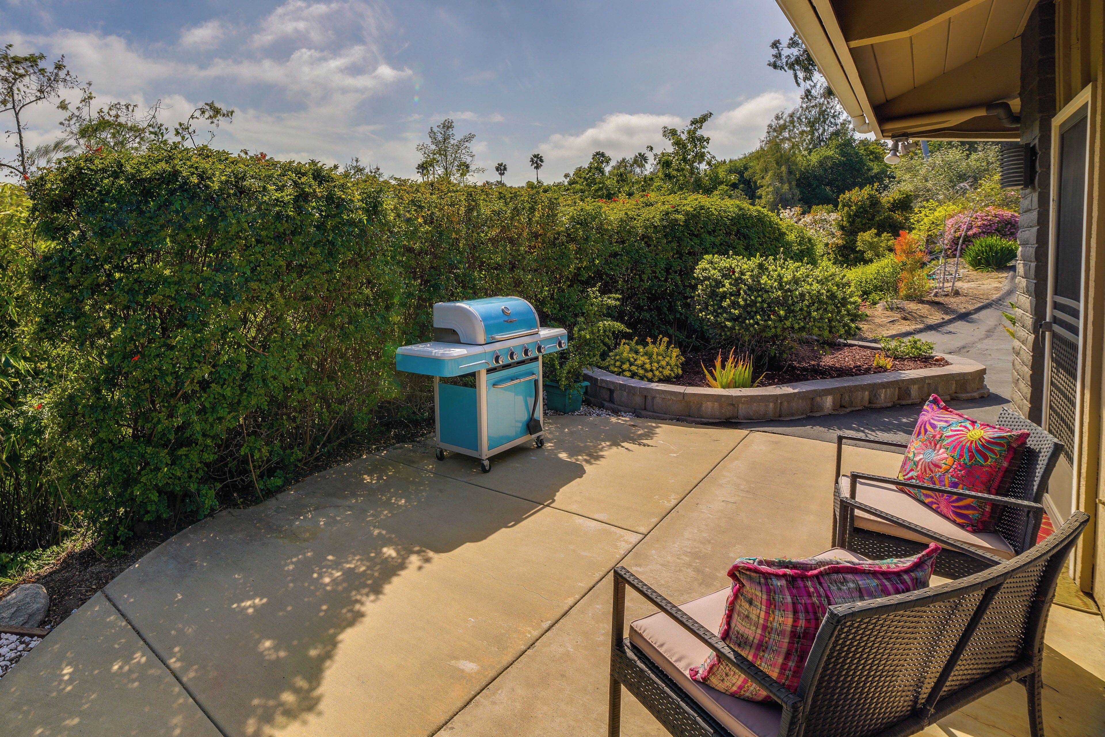 Un patio con parrilla, zona de estar y jardín ajardinado.