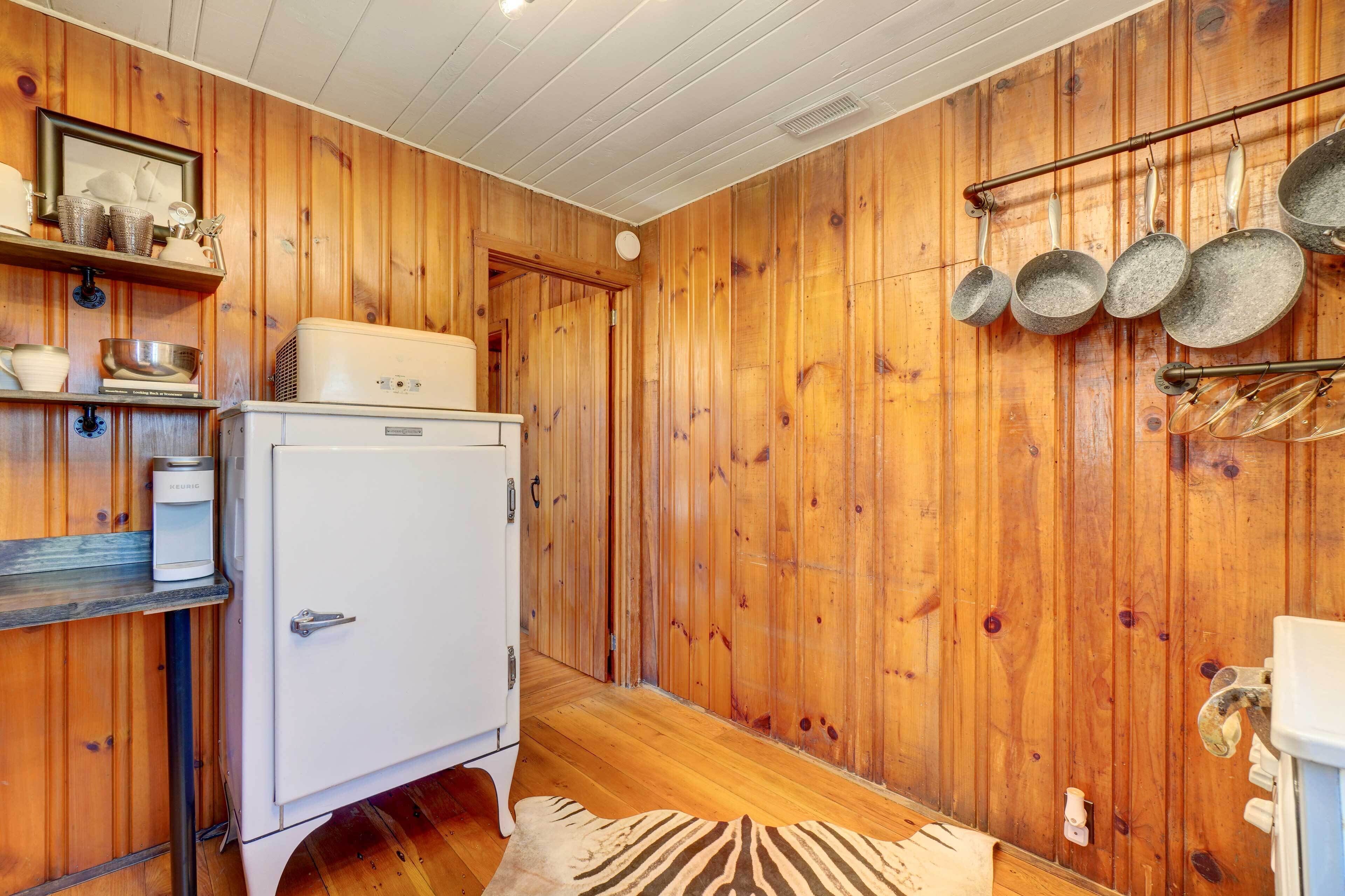 Una cocina compacta con paredes de madera, un refrigerador blanco y un colgador para ollas.