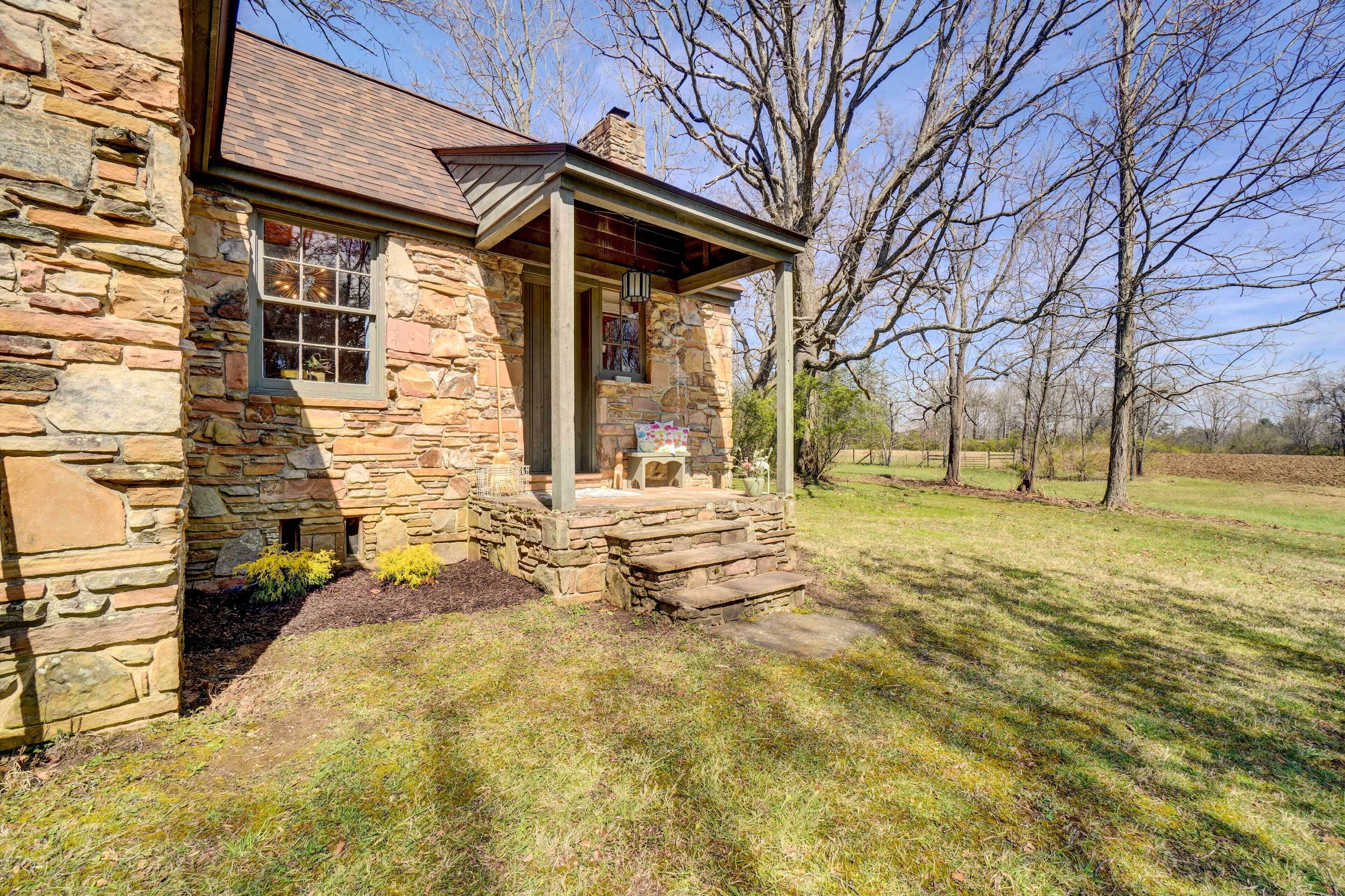 A stone house with a covered porch and a small garden area.