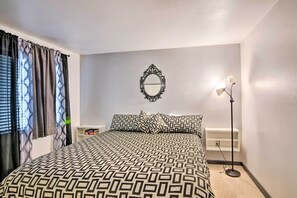 Une chambre à coucher avec une couvre-lit à motifs, une table de chevet, un miroir et une lampe sur pied.
