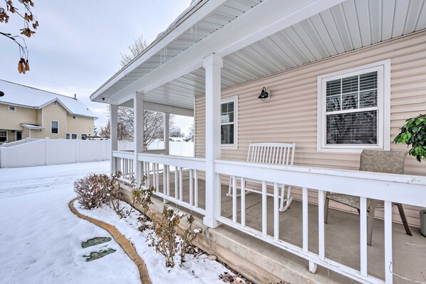A covered porch with a white railing, a bench, and a potted plant. - Meadow Retreat' Near Parks & USU (Logan)