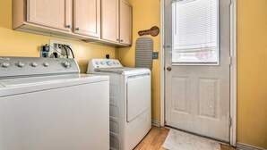 A laundry area with a washing machine, dryer, wooden cabinets, and a door with blinds. - Meadow Retreat' Near Parks & USU (Logan)