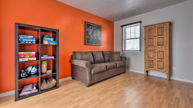 A living room with a brown sofa, a wooden cabinet, and a bookshelf with board games. - Meadow Retreat' Near Parks & USU (Logan)
