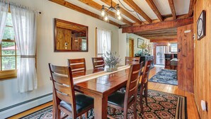 A dining area with wooden tables and chairs, a chandelier, and a view into the kitchen. - Game Room & Yard: Greentown Home Near State Park (Greentown)
