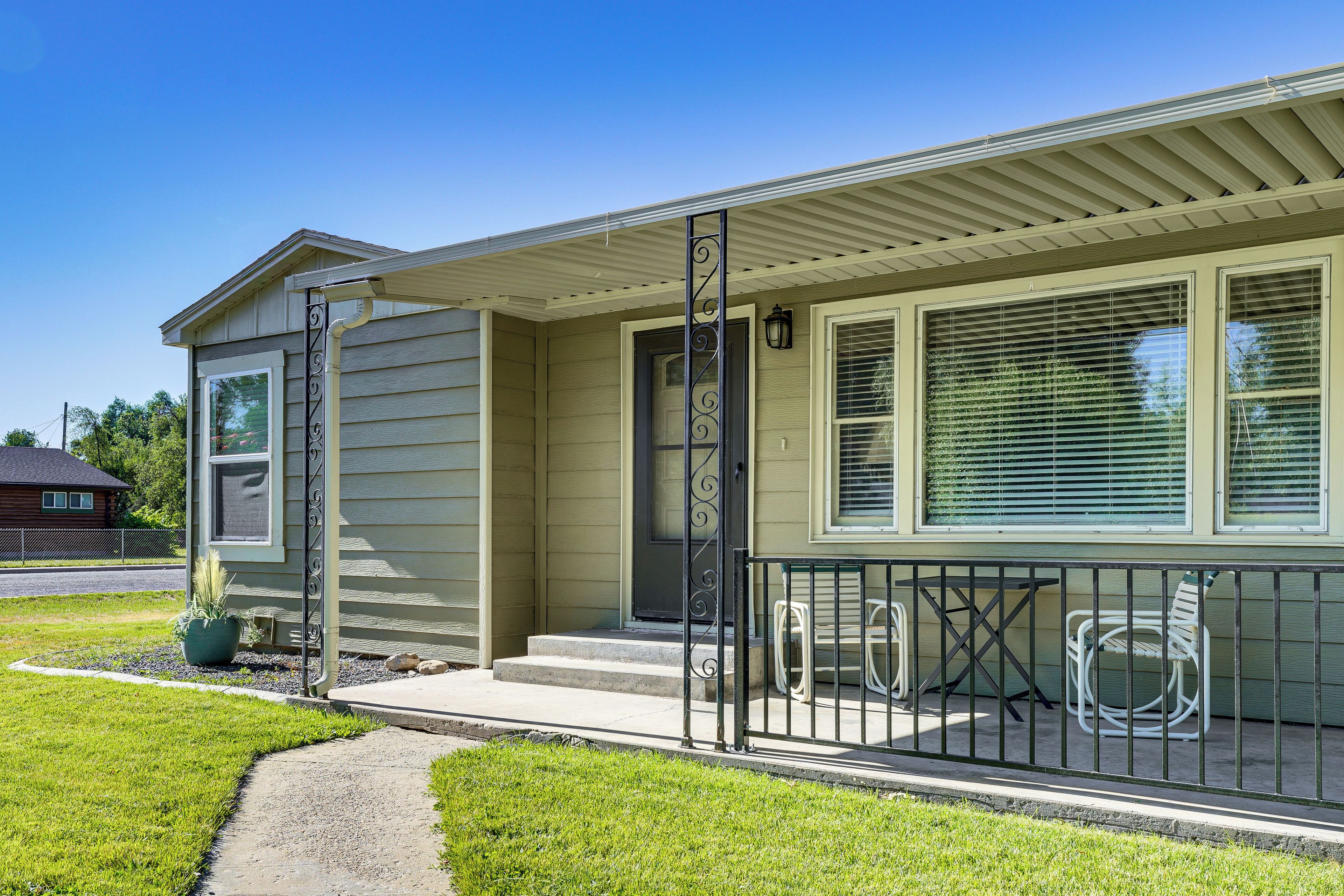 A single-story house with a front porch, a small garden, and a clear sky.
