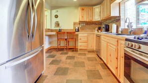 A kitchen with a stainless steel refrigerator, wooden cabinets, a tiled floor, and a built-in oven. - Fruita Vacation Rental: Walk to Downtown! (Fruita)