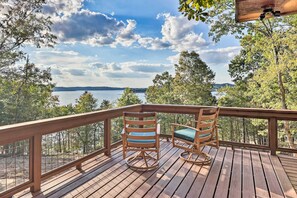 Una terraza de madera con dos mecedoras con vista a un lago.