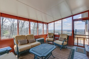Ein Wintergarten mit Blick auf die Landschaft, ausgestattet mit einer Couch, Sesseln und einem Couchtisch.