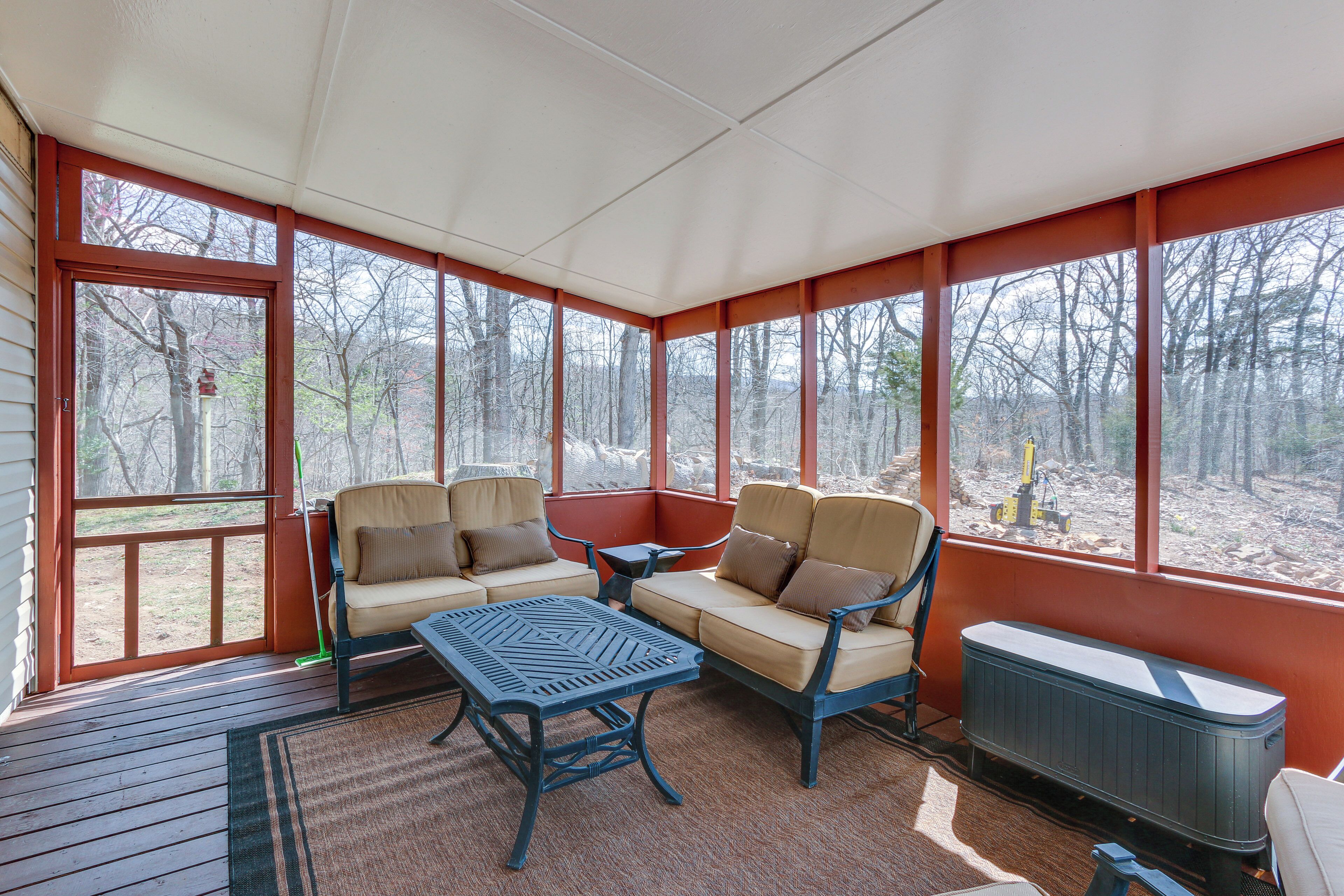 A covered porch with a sofa, chairs, a table, and a radiator.