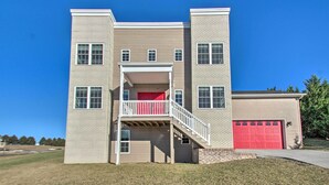 Un edificio de varios pisos con un balcón central, una puerta de garaje roja y una base de ladrillo.