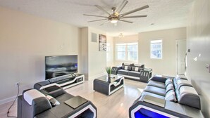 Una sala de estar moderna con un televisor de pantalla plana, un ventilador de techo y un sofá modular.