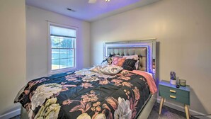 Un dormitorio con una cama, una mesita de noche, un ventilador de techo y una ventana.