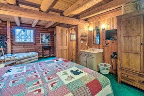 Une chambre confortable dans un chalet en rondins, avec un grand lit, des murs en bois, une fenêtre, un lavabo et un miroir.
