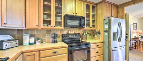 A kitchen with wooden cabinets, a microwave, a stainless steel refrigerator, a stove, and a toaster.