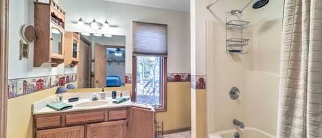 A bathroom with wooden cabinets, a large mirror, a bathtub, and a shower.