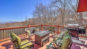 Un terrazzo con mobili da esterno, un barbecue e vista sulle montagne.