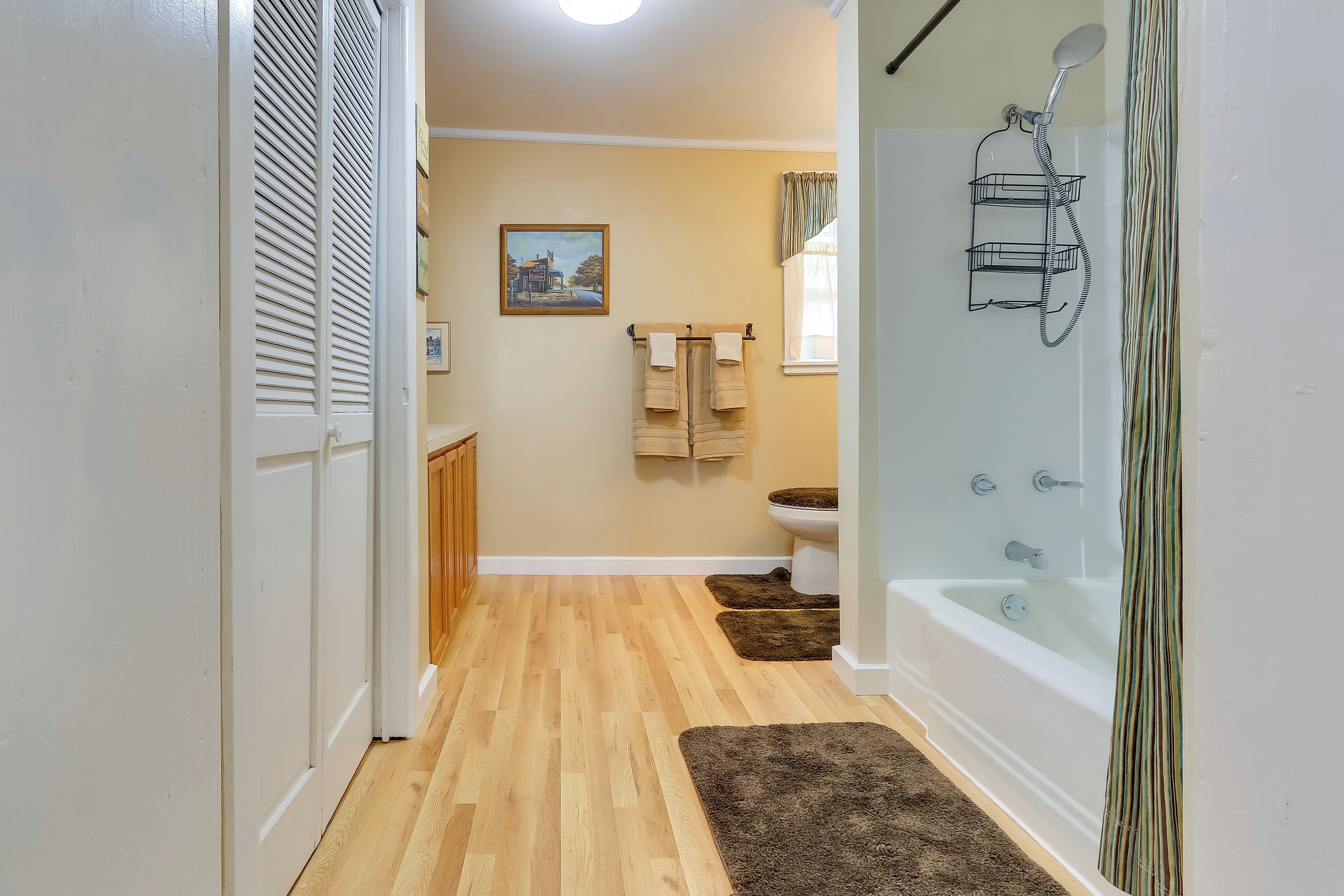 A bathroom with a wooden floor, a bathtub, a shower, and a toilet.