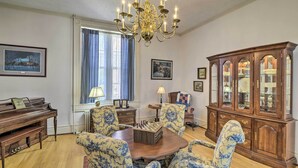 A dining room with a wooden table, blue and white patterned chairs, a chandelier, a piano, and a glass cabinet. - Historic West Virginia Home Built in 1854! (Moorefield)